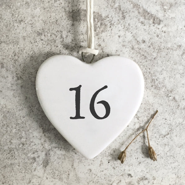 White heart-shaped ornament with the number 16 on a textured gray surface