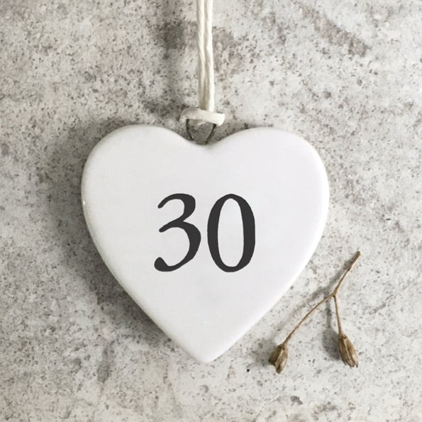 White heart-shaped ornament with the number 30 on a concrete surface