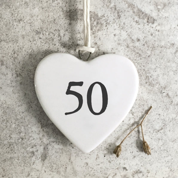 White heart-shaped ornament with the number 50 on a textured gray surface