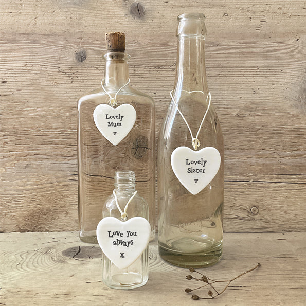 Three glass bottles with heart-shaped tags on a wooden surface