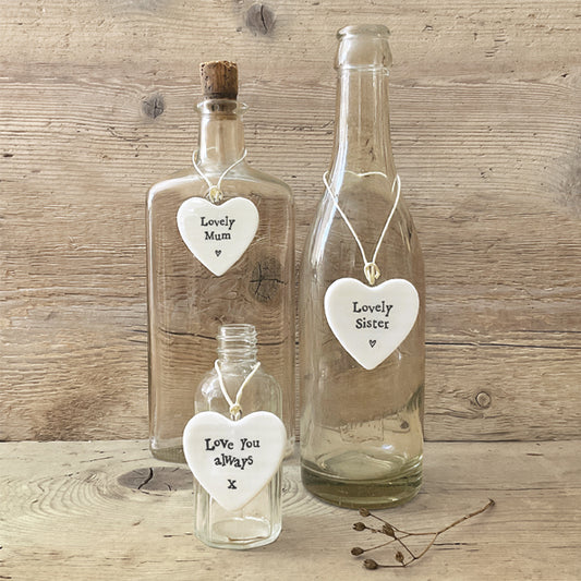 Three glass bottles with heart-shaped tags on a wooden surface
