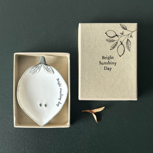 White ceramic lemon shaped dish with 'Bright Sunshiny Day' text in a matching box on a dark background