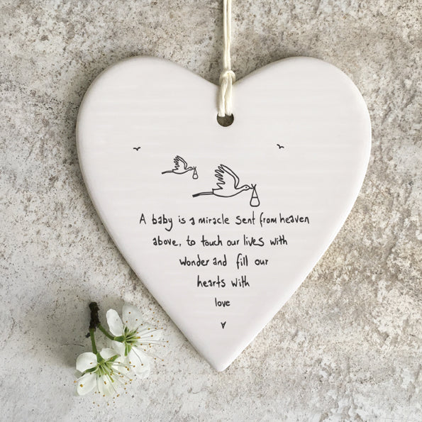 Heart-shaped ceramic ornament with “a baby is a miracle sent from heaven above, to touch our lives with wonder and fill our hearts with love” written on the surface
