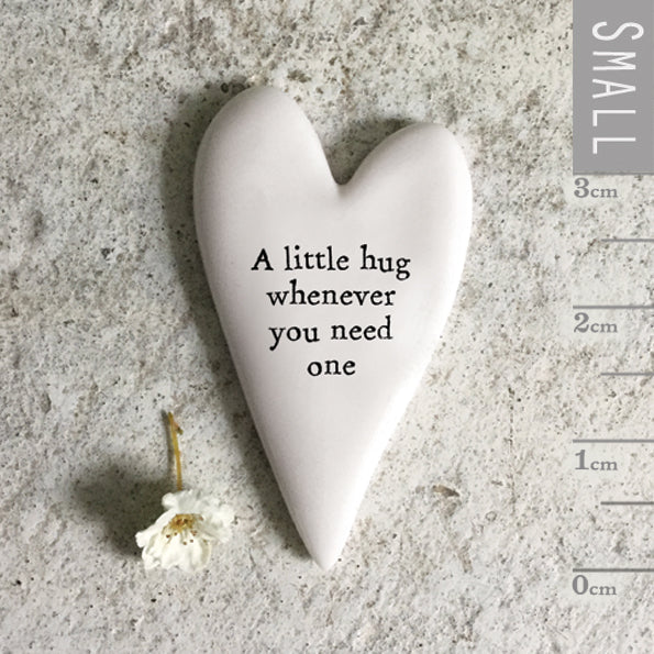 Heart-shaped ceramic object with ‘A little hug whenever you need it’ text on a textured surface with a ruler for scale.