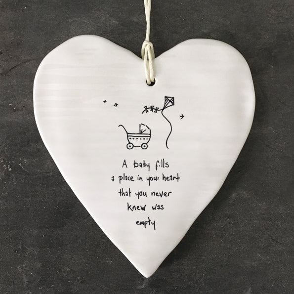 White ceramic heart with “a baby fills a place in your heart you never knew was empty” written on a textured surface.